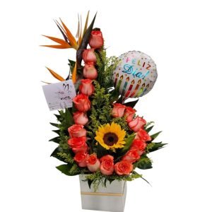 Cubo de rosas salmón, aves del paraíso, un girasol y globo metalizado