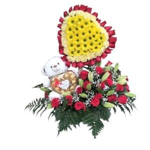 Arreglo en forma de corazón con 60 rosas rojas, margaritas amarillas, lirios blancos, follaje y peluche con chocolates Ferrero